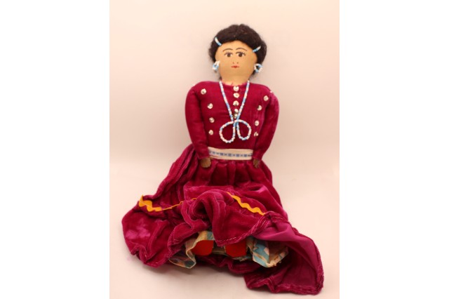doll with beaded necklace and reddish velvet dress 