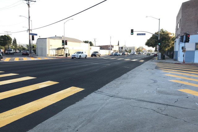 Four sides of an intersection showing freshly painted lines of yellow crosswalks on each street.