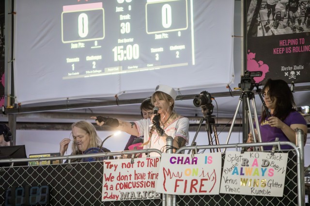 Dressed in a white nurse uniform, Evil E points at the players during a roller derby bout