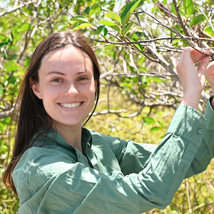 Scientist holds up a branch and smiles at the camera